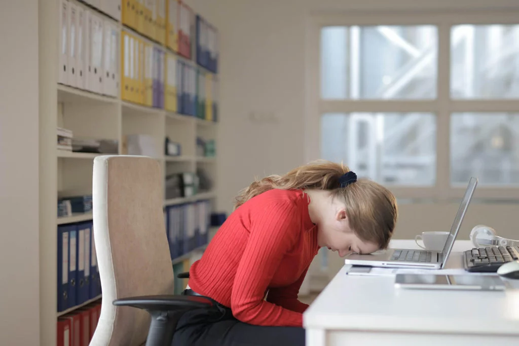 woman in red with head on desk